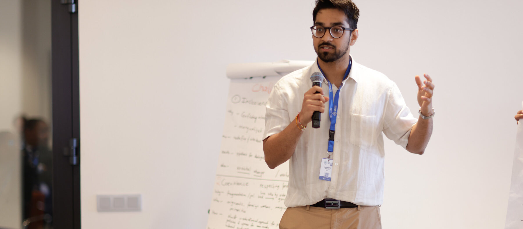 Swapneel Mehta presenting with a microphone beside a flip chart during a workshop session